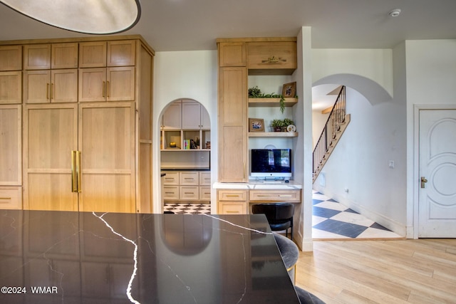 kitchen featuring dark countertops, light brown cabinets, light wood-style flooring, and open shelves