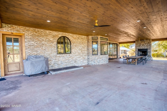 view of patio featuring ceiling fan, an outdoor stone fireplace, and grilling area