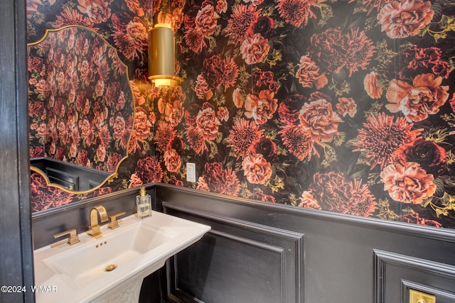 bathroom featuring a sink and wallpapered walls