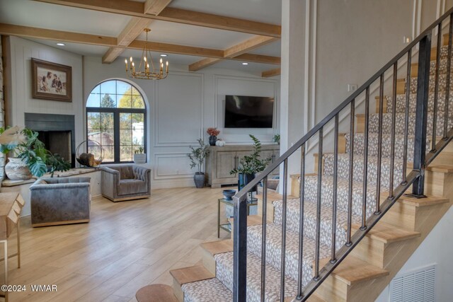 interior space with coffered ceiling, wood finished floors, beamed ceiling, a fireplace, and a decorative wall