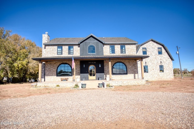 view of front of home featuring a porch, brick siding, and a chimney