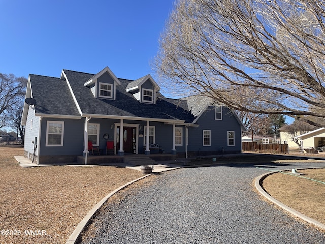 cape cod-style house with covered porch, a shingled roof, and fence