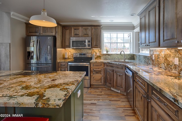 kitchen with stainless steel appliances, a sink, light stone counters, and ornamental molding