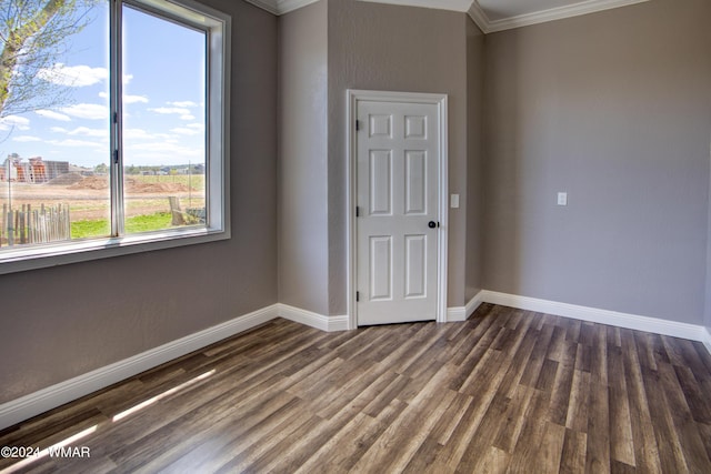 empty room featuring baseboards, dark wood finished floors, and crown molding