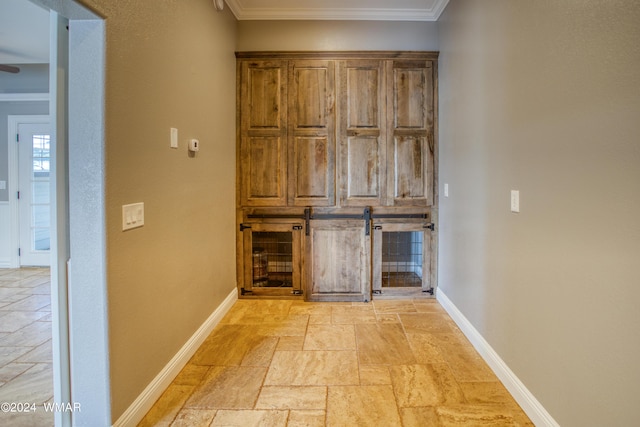 corridor featuring crown molding, stone tile floors, and baseboards