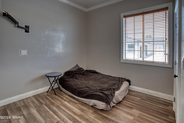 bedroom featuring baseboards, ornamental molding, and wood finished floors