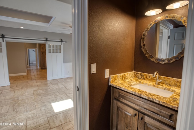 bathroom with ceiling fan, stone finish flooring, and vanity