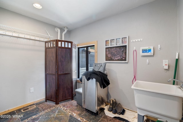 interior space with visible vents, baseboards, stone tile floors, recessed lighting, and a sink