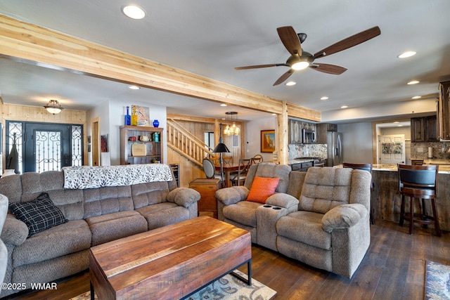 living area featuring stairs, ceiling fan with notable chandelier, recessed lighting, and dark wood-style flooring