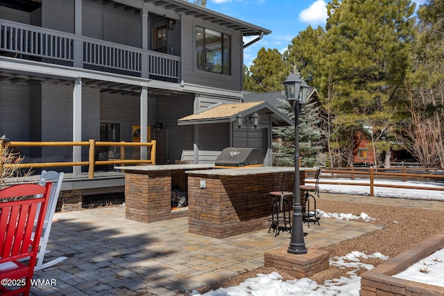 view of patio / terrace with a balcony, grilling area, fence, and an outdoor kitchen