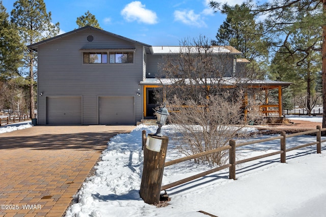 view of front of house featuring decorative driveway, a garage, and fence