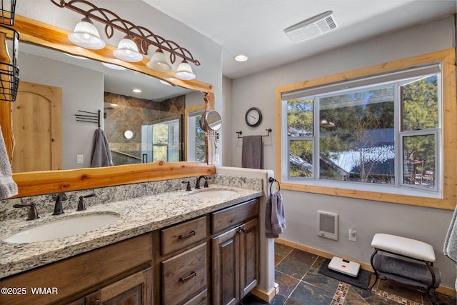 full bath featuring stone tile floors, baseboards, visible vents, and a sink