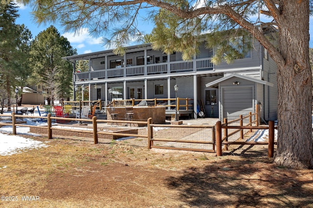 back of house featuring an outdoor structure, a balcony, and fence