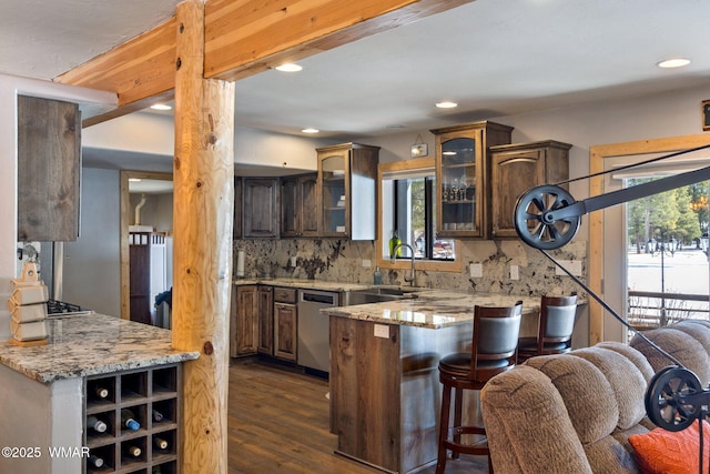 kitchen featuring a peninsula, a sink, glass insert cabinets, stainless steel dishwasher, and tasteful backsplash