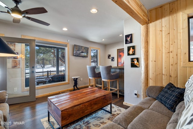 living room with beam ceiling, wood finished floors, recessed lighting, a bar, and baseboards