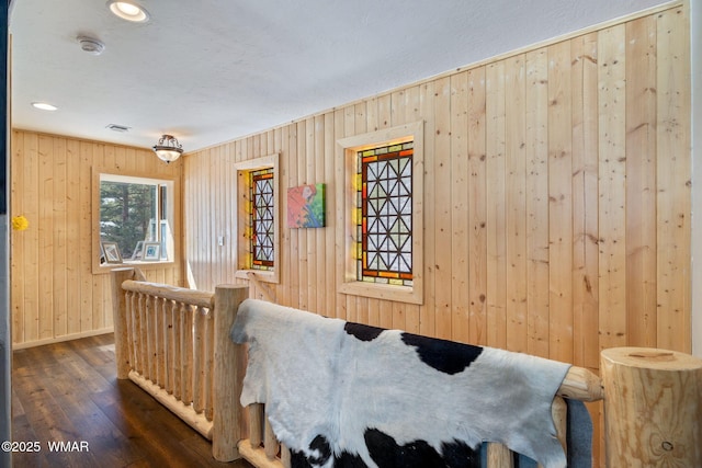 bedroom featuring visible vents, baseboards, dark wood finished floors, and wood walls