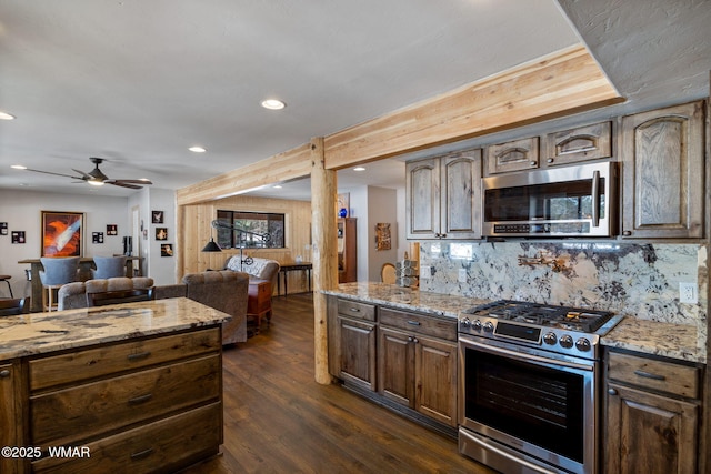 kitchen featuring open floor plan, light stone countertops, dark wood-style flooring, and appliances with stainless steel finishes