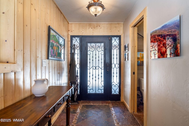 entryway with stone tile floors, wooden walls, and a healthy amount of sunlight