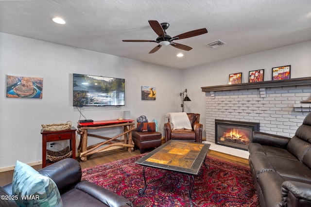 living room featuring wood finished floors, visible vents, baseboards, a fireplace, and recessed lighting