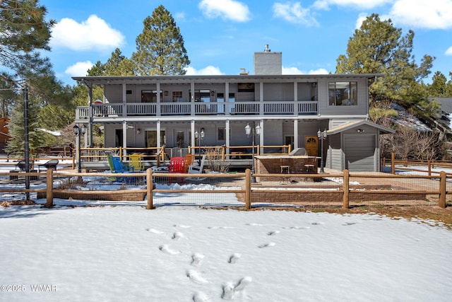 snow covered property with a chimney and an outdoor structure