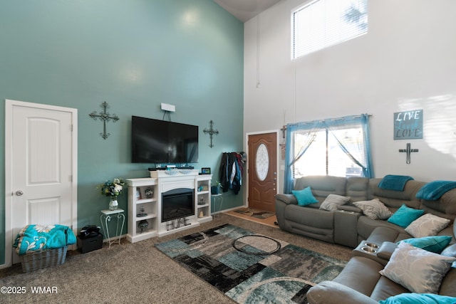 1275 Flag Hollow Rd, Lakeside, AZ 85929 - carpeted living room featuring a towering ceiling, plenty of natural light, a glass covered fireplace, and baseboards