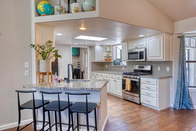 1421 N 36th Dr, Show Low, AZ 85901 - kitchen featuring appliances with stainless steel finishes, open shelves, a sink, a peninsula, and backsplash