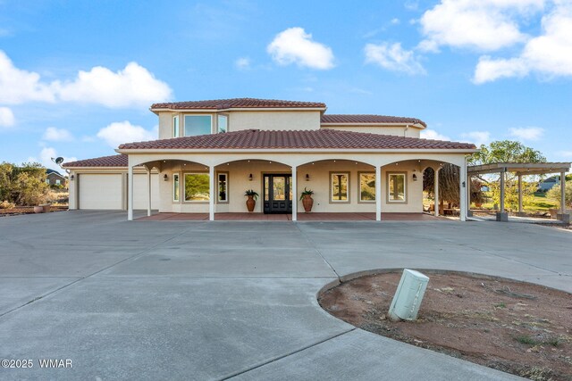 view of front of property featuring a porch, concrete driveway, stucco siding, a tiled roof, and an attached garage
