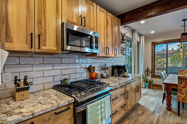 2737 Skyhawk Dr, Overgaard, AZ 85933 - kitchen with light stone counters, beamed ceiling, decorative backsplash, appliances with stainless steel finishes, and wood finished floors