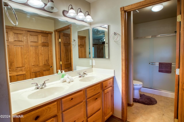 bathroom with toilet, tile patterned flooring, double vanity, and a sink