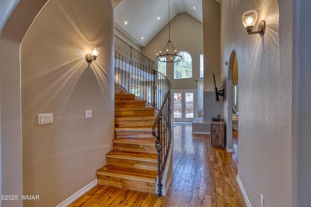 4701 S Manzanita Way, Show Low, AZ 85901 - staircase featuring wood-type flooring, high vaulted ceiling, a chandelier, baseboards, and arched walkways
