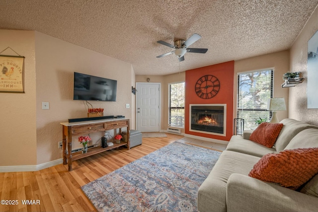 living area featuring a textured ceiling, a glass covered fireplace, plenty of natural light, and wood finished floors