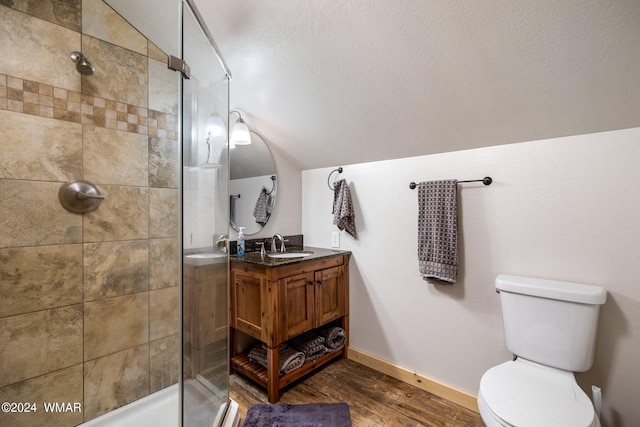 full bath featuring lofted ceiling, toilet, vanity, wood finished floors, and tiled shower