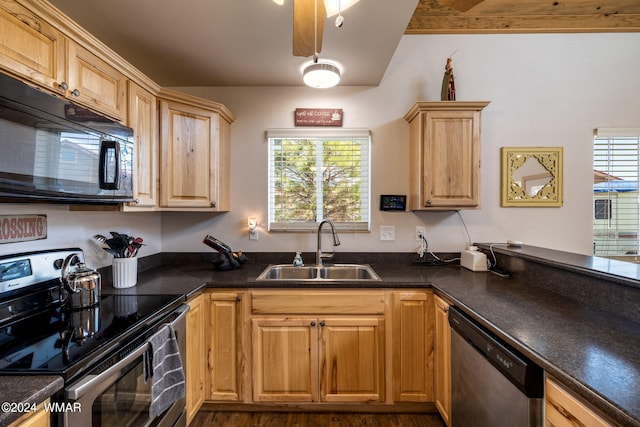 kitchen with stainless steel appliances, dark countertops, a sink, and light brown cabinetry