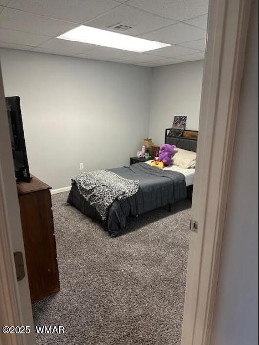 carpeted bedroom featuring a drop ceiling and baseboards