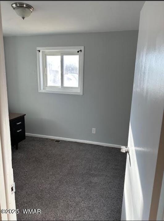 interior space featuring dark carpet and baseboards