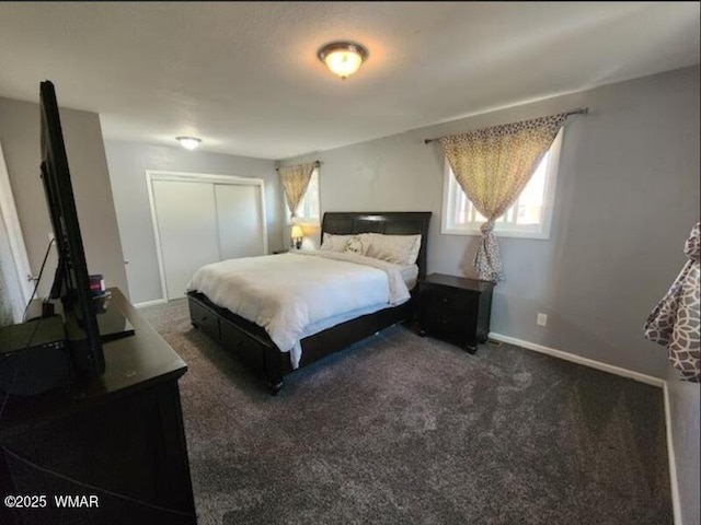 bedroom featuring baseboards, dark carpet, and a closet