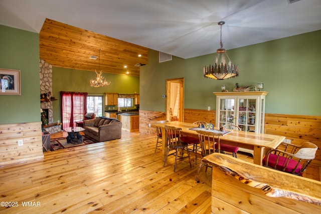 5238 Buck Springs Rd, Pinetop, AZ 85935 - dining space featuring a chandelier, a wainscoted wall, light wood finished floors, wood walls, and vaulted ceiling