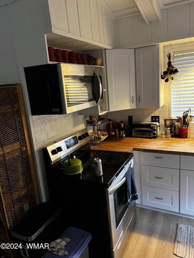 kitchen featuring stainless steel appliances, tasteful backsplash, wood counters, and white cabinetry