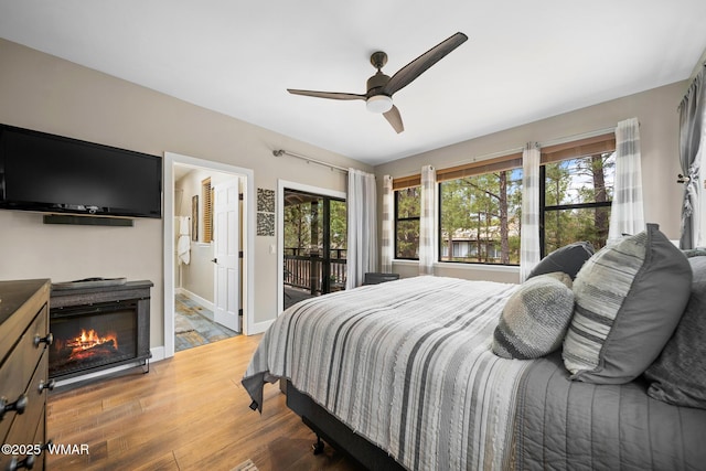 bedroom with access to exterior, wood finished floors, multiple windows, and ceiling fan