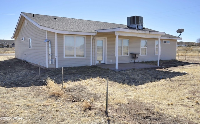 back of property with central AC, a shingled roof, and a patio