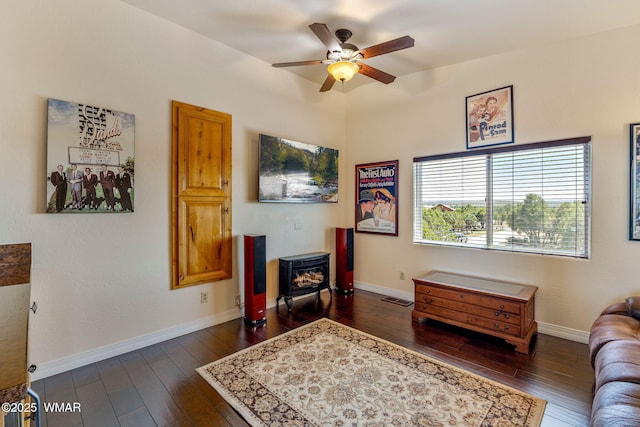 2335 Voyager Cir, Overgaard, AZ 85933 - living area featuring a wood stove, a ceiling fan, dark wood finished floors, and baseboards