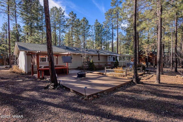 rear view of property featuring a wooden deck and a jacuzzi