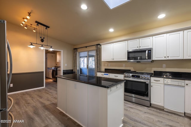 kitchen featuring dark countertops, white cabinetry, stainless steel appliances, and decorative light fixtures