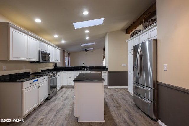 kitchen with stainless steel appliances, dark countertops, white cabinetry, a kitchen island, and a peninsula