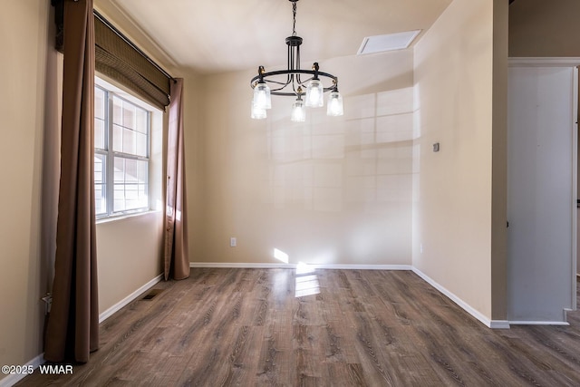 unfurnished dining area with a notable chandelier, dark wood finished floors, and baseboards