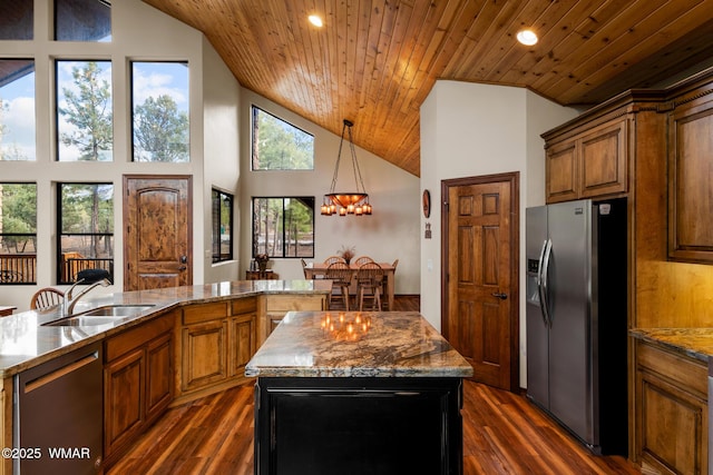 kitchen featuring dishwasher, brown cabinets, a center island, stainless steel refrigerator with ice dispenser, and a sink