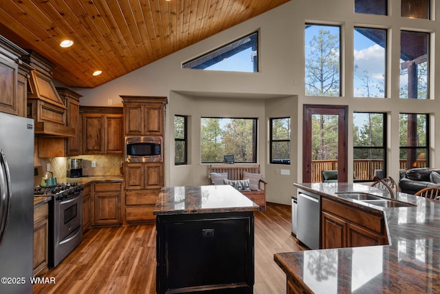 kitchen with wooden ceiling, a sink, open floor plan, appliances with stainless steel finishes, and a center island