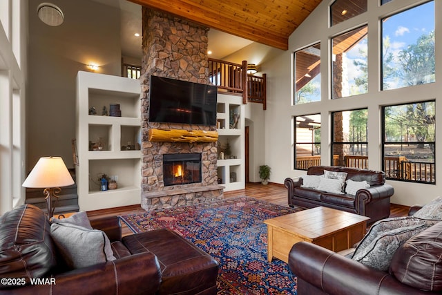 living room featuring high vaulted ceiling, wooden ceiling, a fireplace, and wood finished floors