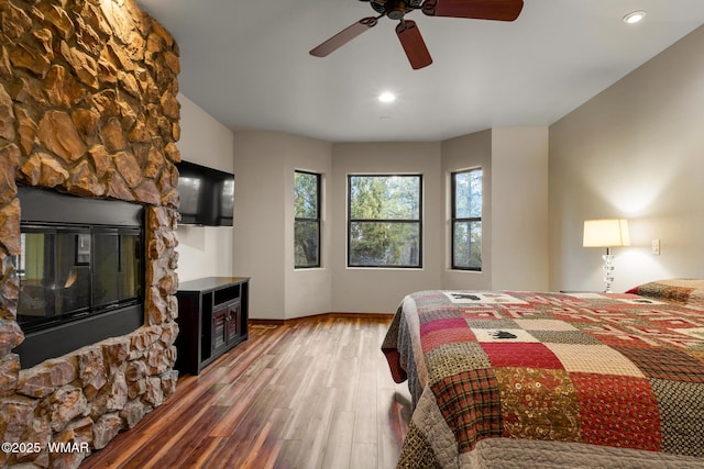 bedroom with a fireplace, recessed lighting, a ceiling fan, wood finished floors, and baseboards