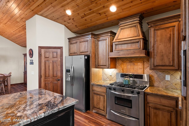 kitchen with custom exhaust hood, appliances with stainless steel finishes, dark stone counters, and lofted ceiling